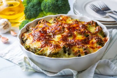 Casserole Cauliflower and broccoli baked with cheese sauce in a pot close-up on a wooden table. Horizontal top view from above. Broccoli gratin.