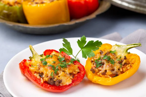 stock image Stuffed peppers, halves of peppers stuffed with rice, dried tomatoes, herbs and cheese in a baking dish on a blue wooden table, top view. (Turkish name; biber dolmasi)