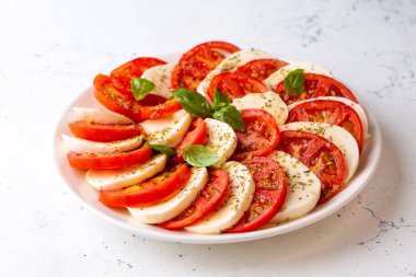 Dilimlenmiş domates, mozzarella, fesleğen, zeytin yağı ile İtalyan Caprese salatası