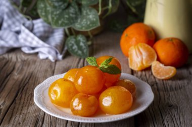 Cam kavanozda mandalina reçeli ve etrafında meyve