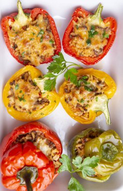 Doldurulmuş biber, pirinçle doldurulmuş yarım biber, kurutulmuş domates, otlar ve peynir mavi ahşap bir masada fırın kabında, üst manzara. (Türkçe adı; biber dolmasi)