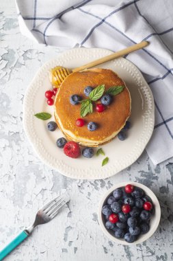 Sağlıklı yaz kahvaltısı, ev yapımı klasik Amerikan krepleri taze meyve ve bal, sabah açık gri taş arka plan fotokopi alanı üst görünüm