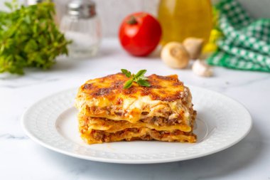 Portion of ground beef lasagna topped with melted cheese and garnished with fresh parsley served on a plate in close view for a menu