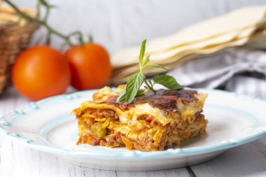 Portion of ground beef lasagna topped with melted cheese and garnished with fresh parsley served on a plate in close view for a menu