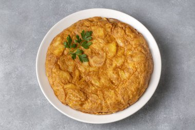 Patatesli İspanyol omleti, gri beton zeminde tipik İspanyol mutfağı. Tortilla Espanola. Türkçe adı: Yumurtali patatesi