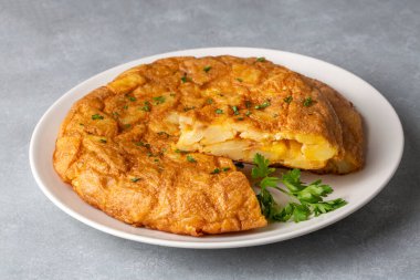 Spanish omelette with potatoes, typical spanish cuisine on gray concrete floor. Tortilla Espanola. Turkish name; Yumurtali patates