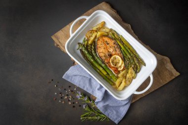 Izgara, fırında somon, kuşkonmaz ve patatesle servis edilir..