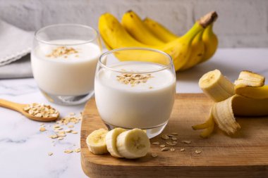 Hafif arka planda cam kavanozda vejetaryen muz ve yulaf ezmeli smoothie. Sağlıklı yiyecekler.