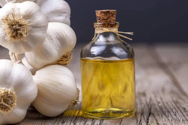 Fresh healthy garlic oil on the wooden background.
