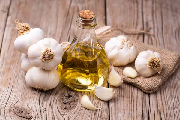 Fresh healthy garlic oil on the wooden background.
