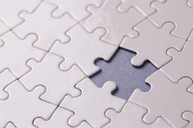 Missing jigsaw puzzle pieces. Business concept. Fragment of a folded white jigsaw puzzle and a pile of uncombed puzzle elements against