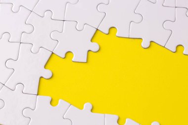 Missing jigsaw puzzle pieces. Business concept. Fragment of a folded white jigsaw puzzle and a pile of uncombed puzzle elements against