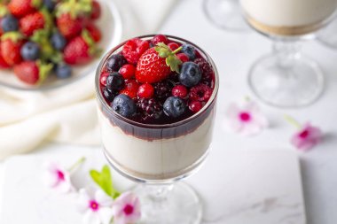 Sütlü tatlı, üzerine orman meyveleri ve meyve sosu konmuş lezzetli puding..