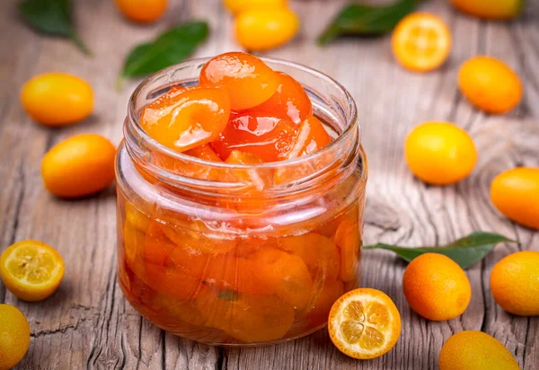 Homemade kumquat jam in jar and fresh kumquats, top view