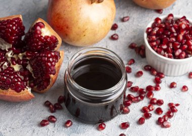 Glass bottle of pomegranate sour sauce with fresh ripe whole and split pomegranate fruit (Turkish name; nar eksisi)