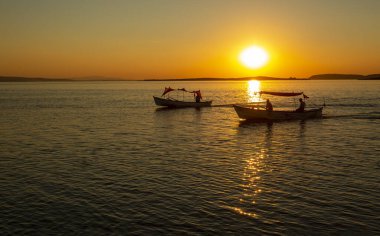Bursa, Bursa 'daki Golyazi' de günbatımının güzel manzarası. Siluetler, tekneler ve Ulubat Gölü üzerindeki bulutlar.