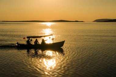 Bursa, Bursa 'daki Golyazi' de günbatımının güzel manzarası. Siluetler, tekneler ve Ulubat Gölü üzerindeki bulutlar.