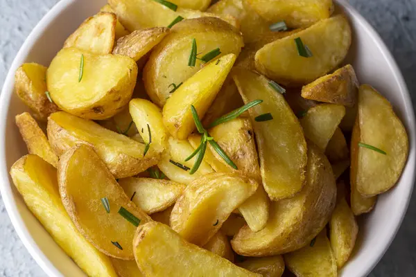 Kızarmış patates kamışı, otlar ve tabakta deniz tuzu, üst görünüm (Türk adı; elma dilim patatesi))