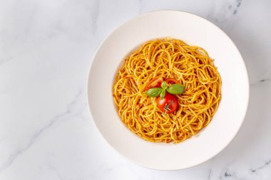 Lezzetli iştah açıcı klasik İtalyan spagettisi domates soslu makarna, peynirli parmesan peynirli fesleğen ve beyaz mermer masada makarna pişirmek için malzemeler..