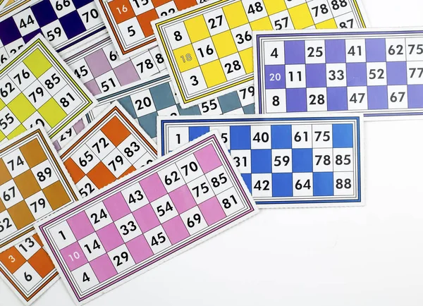 Colorful bingo game cards and numbers on white background, close up, isolated.