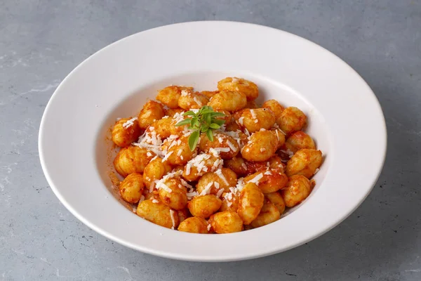Geleneksel İtalyan yemeği, domates soslu patates gnocchi, parmesan peyniri ve koyu sehpada taze fesleğen. Üst Manzara. Sağlıklı yemek..