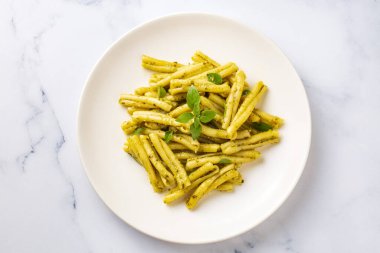 Gri arka planda kişniş soslu Casarecce makarna, üst manzara. Lezzetli vejetaryen yemeği.