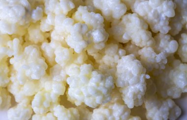 Kefir, kefir taneli mayalanmış süt içeceği. Ev yapımı kefir bir bardakta duruyor, kefir taneleri ve sütün yanında.