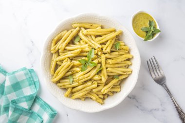 Gri arka planda kişniş soslu Casarecce makarna, üst manzara. Lezzetli vejetaryen yemeği.