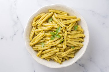 Gri arka planda kişniş soslu Casarecce makarna, üst manzara. Lezzetli vejetaryen yemeği.