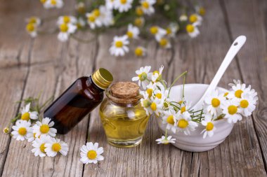 Essential oil in glass bottle with fresh chamomile flowers and variete herbal, beauty treatment.