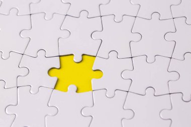 Missing jigsaw puzzle pieces. Business concept. Fragment of a folded white jigsaw puzzle and a pile of uncombed puzzle elements against