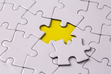 Missing jigsaw puzzle pieces. Business concept. Fragment of a folded white jigsaw puzzle and a pile of uncombed puzzle elements against
