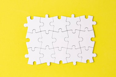Missing jigsaw puzzle pieces. Business concept. Fragment of a folded white jigsaw puzzle and a pile of uncombed puzzle elements against