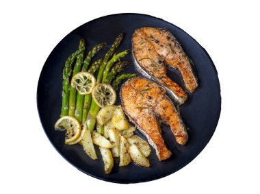 Izgara, fırında somon, kuşkonmaz ve patatesle servis edilir..