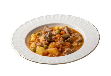 Beyaz tabakta patates, bezelye ve domatesli Türk tas kebabı. Türkçe adı: Tas kebabi