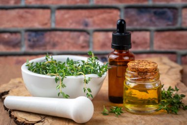 Bir şişe kekik yağı ve taze kekik.