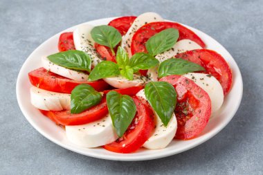 Dilimlenmiş domates, mozzarella, fesleğen, zeytin yağı ile İtalyan Caprese salatası