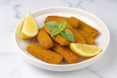 Balık ve patates kızartması. Ekmek kırıntıları ve limon sosuyla servis edilen kızarmış balık kroketlerine yakın olsun.