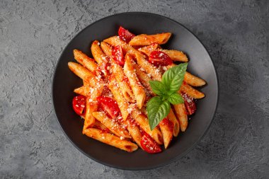 Klasik İtalyan usulü makarna penne alla arrabiata fesleğen ve taze rendelenmiş parmesan peyniri. Acı soslu arrabbiata soslu makarna..