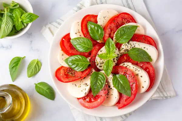 Dilimlenmiş domates, mozzarella, fesleğen, zeytin yağı ile İtalyan Caprese salatası
