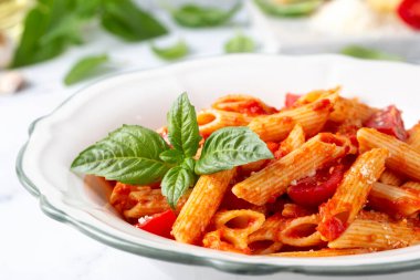 Klasik İtalyan usulü makarna penne alla arrabiata fesleğen ve taze rendelenmiş parmesan peyniri. Acı soslu arrabbiata soslu makarna..