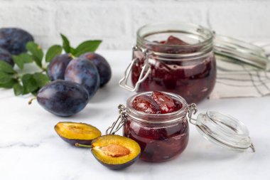 Mavi seramik kasede ev yapımı erik reçeli ve beyaz ahşap arka planda böğürtlen..