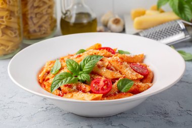 Klasik İtalyan usulü makarna penne alla arrabiata fesleğen ve taze rendelenmiş parmesan peyniri. Acı soslu arrabbiata soslu makarna..