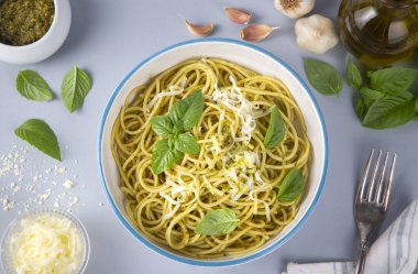 Pesto soslu lezzetli makarna, fesleğen ve çatal bıçak.