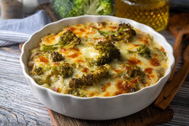 Güveçte brokoli, ahşap bir masada, yakın plan bir kapta peynir sosuyla pişirilmiş. Yukarıdan yatay üst görünüm. Brokoli graten..