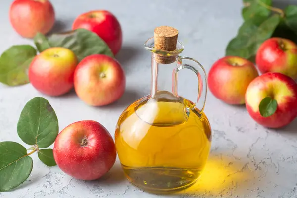 Elma sirkesi mayalanmış meyve, taze organik, olgun yapraklı kırmızı elmalarla dolu cam bir şişeye konur.
