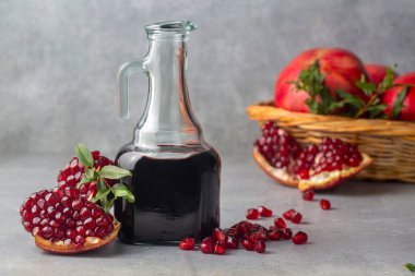 Glass bottle of pomegranate sour sauce with fresh ripe whole and split pomegranate fruit (Turkish name; nar eksisi)