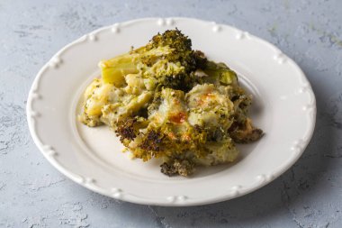 Casserole Cauliflower and broccoli baked with cheese sauce in a pot close-up on a wooden table. Horizontal top view from above. Broccoli gratin.
