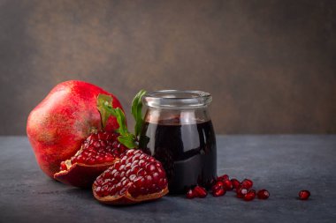 Glass bottle of pomegranate sour sauce with fresh ripe whole and split pomegranate fruit (Turkish name; nar eksisi)
