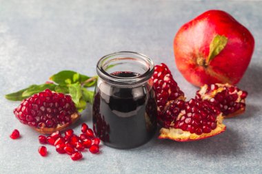 Glass bottle of pomegranate sour sauce with fresh ripe whole and split pomegranate fruit (Turkish name; nar eksisi)